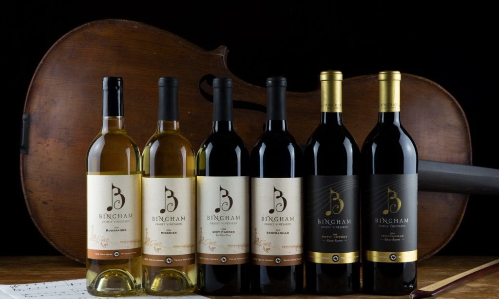 line of bingham family vineyards wine bottles in front of a cello