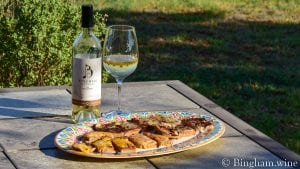 cheese bread on a plater with bottle of bingham family vineyards 2019 Marsanne and glass