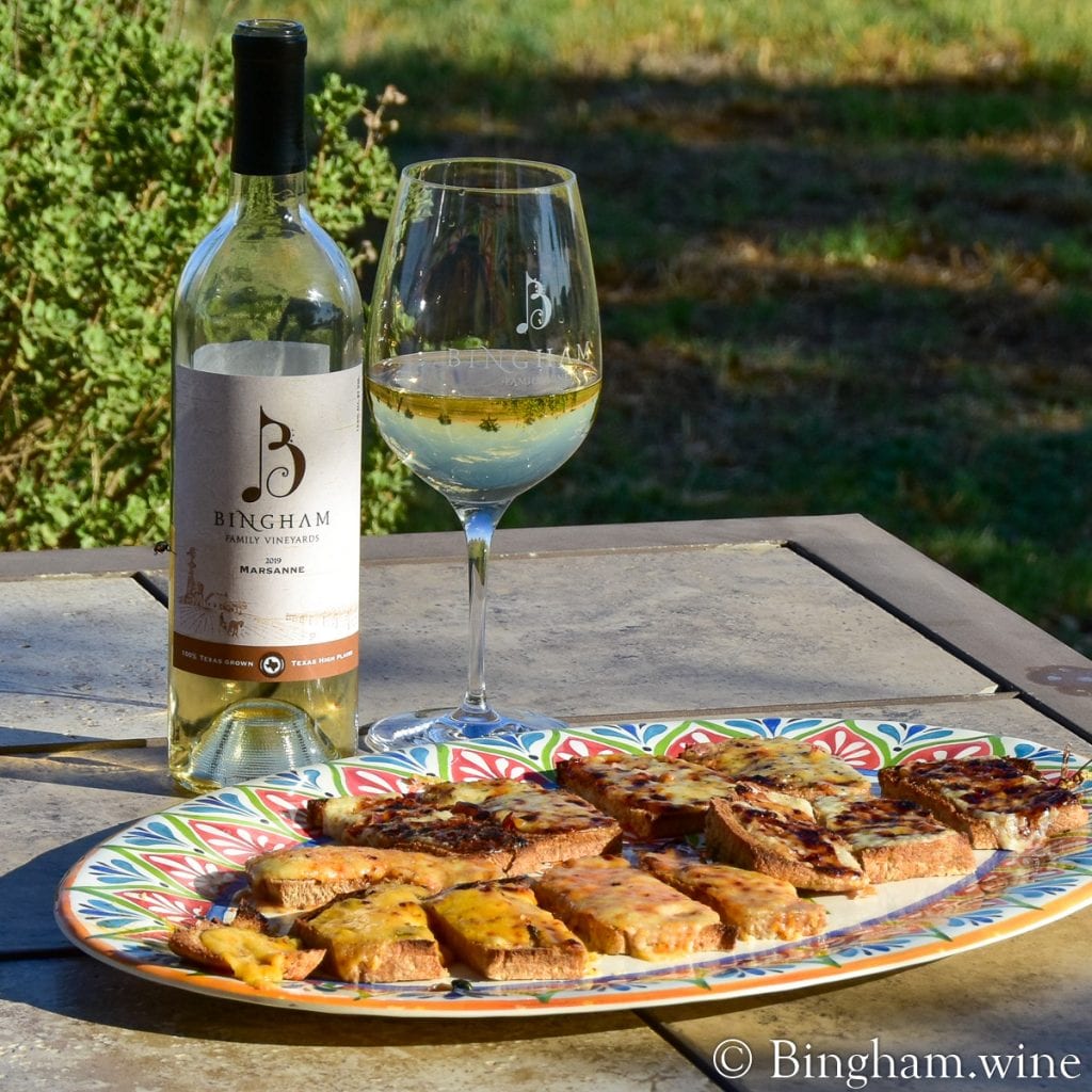 20.05.18_Basil-Oregano_048.1200.web_.1x1 | Bingham Family Vineyards cheese bread on a plater with bottle of bingham family vineyards 2019 Marsanne and glass