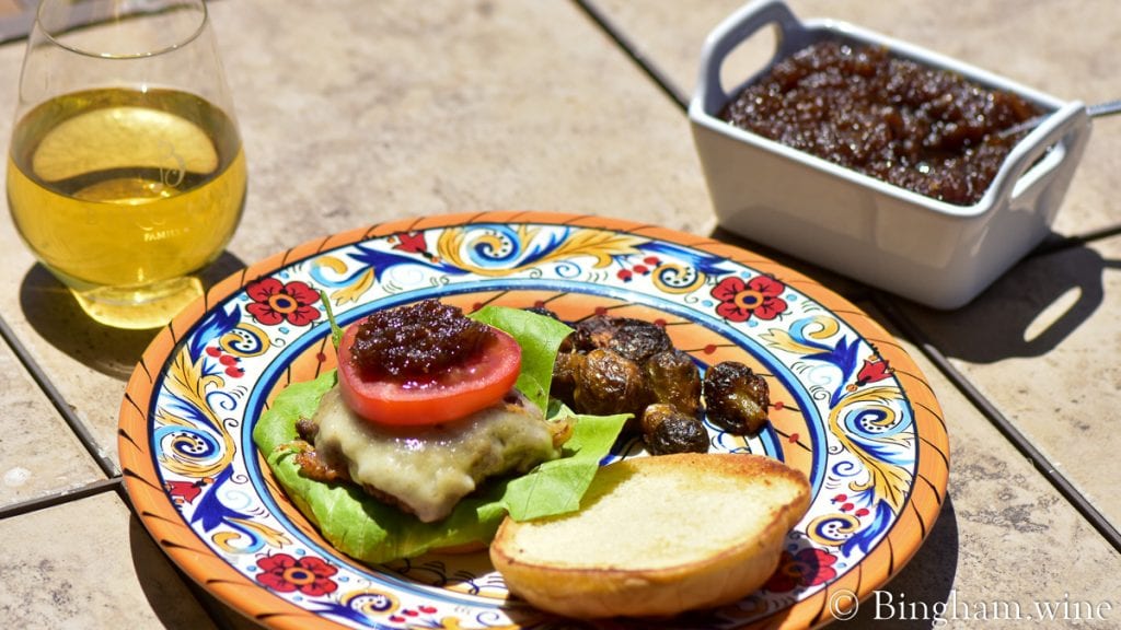onion jam tomatoes lettuce burger with glass of wine