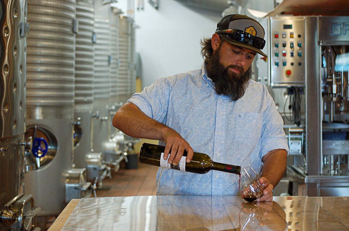 Sam Jennings pouring wine into a glass for a tasting.