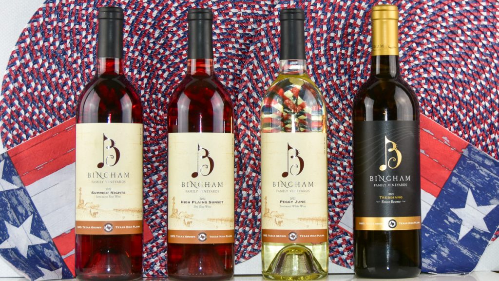 | Bingham Family Vineyards Four bottles of Bingham Family Vineyards wine against a backdrop of red, white, and blue