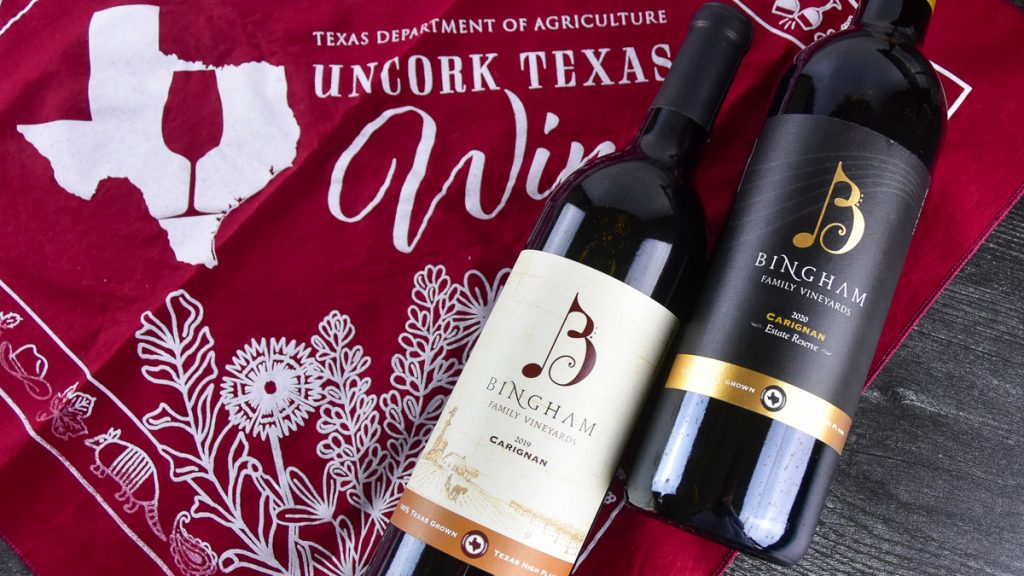 bottles of 2019 Bingham Family Vineyards Carignan and 2020 Reserve Carignan lying on Texas Department of Agriculture Uncork Texas wine red kerchief