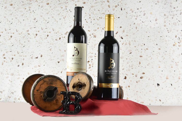 A bottle of Bingham Family Vineyards Mourvèdre and a Reserve Mourvèdre with wooden spools.