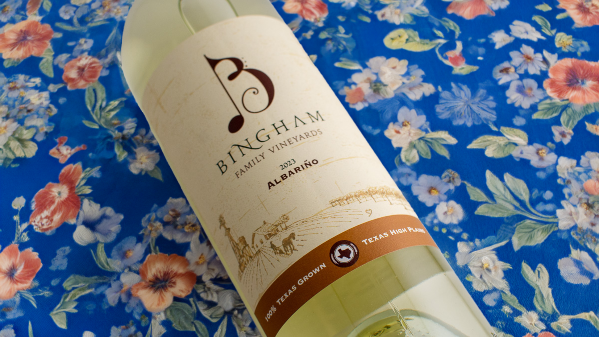 bottle of 2023 Albariño lying on a blue floral tablecloth