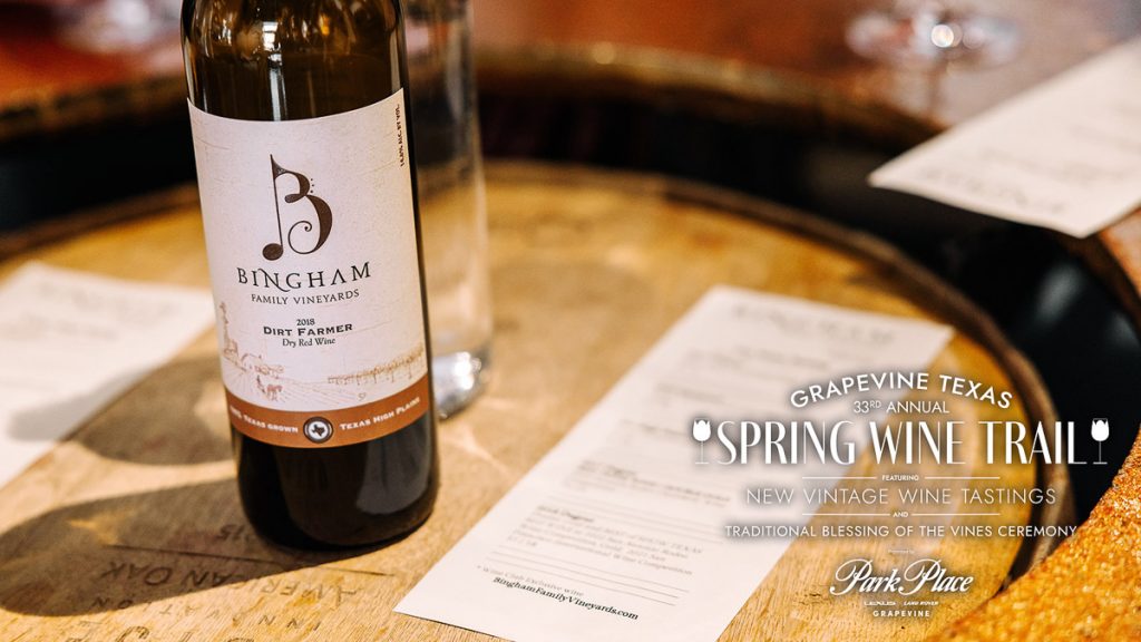 Wine_MainSt_3 1-1200-web-16x9 | Bingham Family Vineyards 33rd Annual Grapevine Spring Wine Trail, New Vintage Wine Tastings and Traditional Blessings of the Vines Ceremony, April 12, 2025 - Bottle of Bingham Family Vineyards Dirt Farmer, red wine blend, next to a tasting sheet set on a wine barrel.