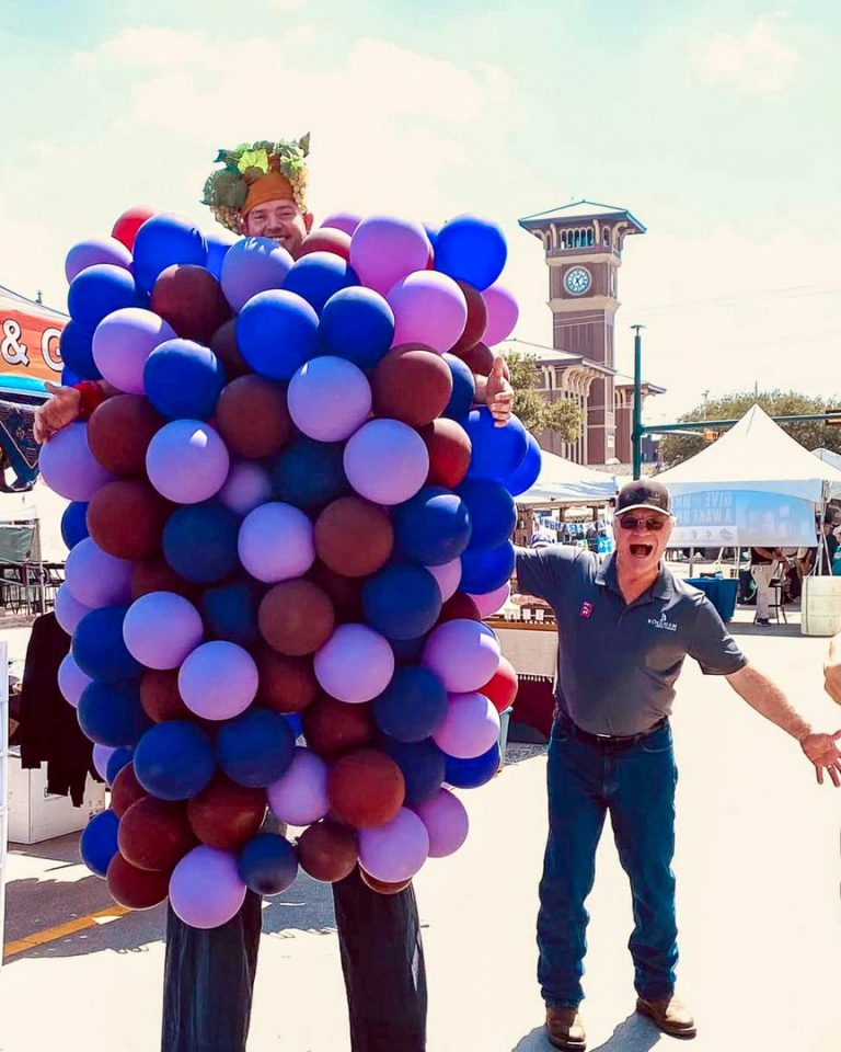 Cliff-Grapefest 4x5 web | Bingham Family Vineyards Cliff Bingham next to a person dressed as a grape cluster at Grapefest in Grapevine, Texas