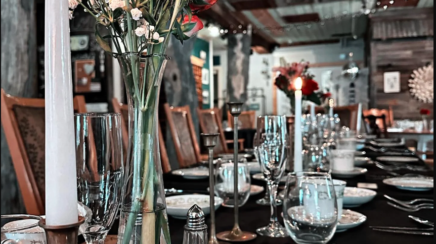 Elegant dining table set for a formal event with candles, glassware, and tall floral centerpiece in a rustic restaurant, Vintage Cork, Ben Wheeler, Texas