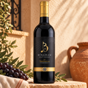 2022 Reserve Tempranillo: Bingham Family Vineyards 2022 Reserve Tempranillo bottle in a warm Spanish-inspired stucco setting with grapes, olive leaves, and a clay pot.